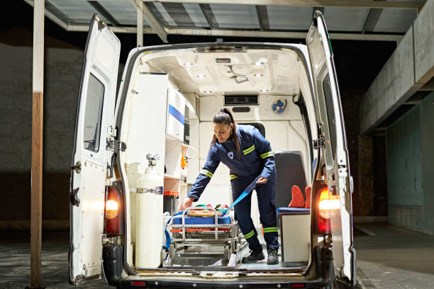 istockphoto-1584850227-612×612 Full length view of uniformed woman standing in emergency vehicle and straightening spinal board on portable stretcher.